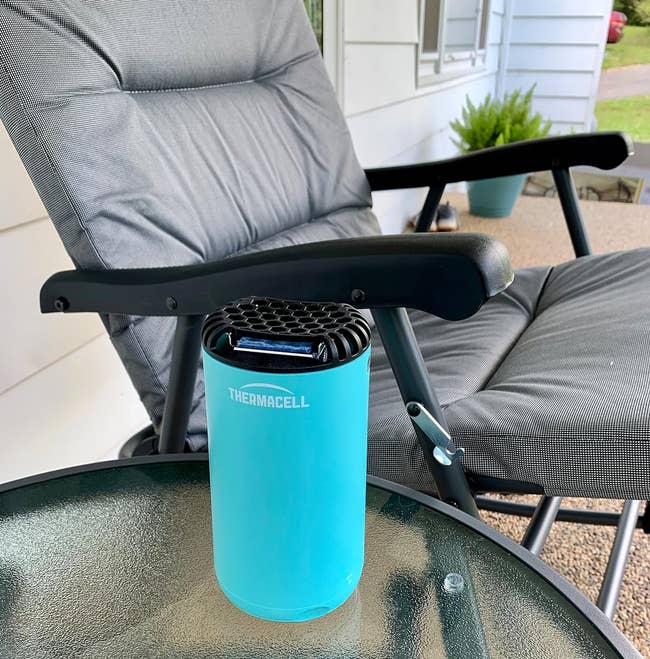 Thermacell mosquito repeller on outdoor glass table with a chair in the background