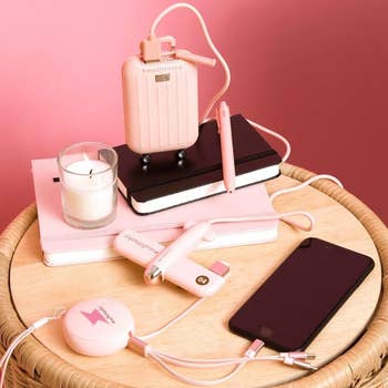 Various pinkish  tech gadgets and notebooks are arranged connected  a circular  wicker table, including a smartphone, powerfulness  banks, and a USB charger