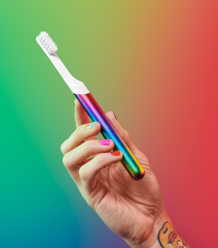 a model holding the toothbrush that has rainbow colors over it