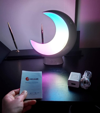 the moon glowing white with a bit of blue and pink in a dark room