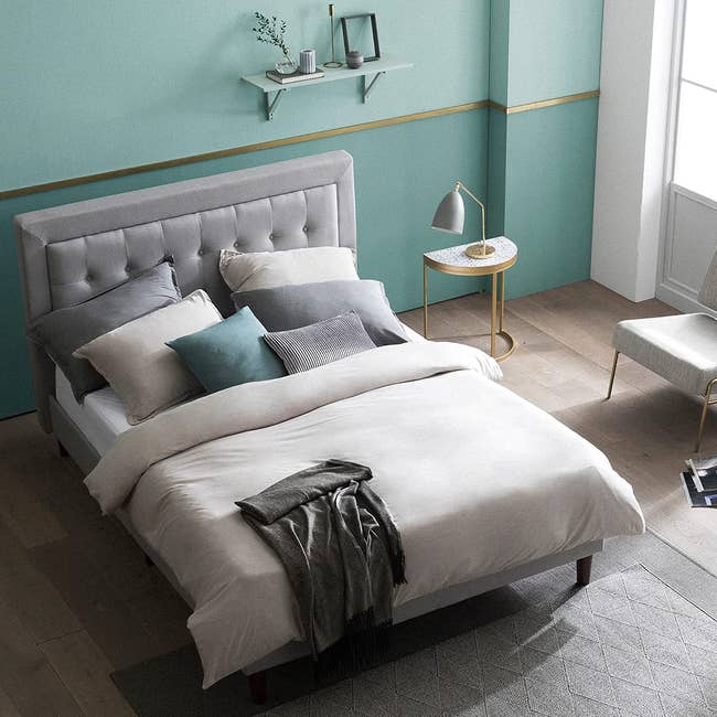 a bed with a gray, tufted upholstered bed frame