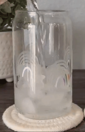 Water pouring into a clear glass and changing color to show rainbow patterned designs on the side of the glass 