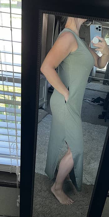 A reviewer taking a selfie in the mirror while wearing the dress in an olive color