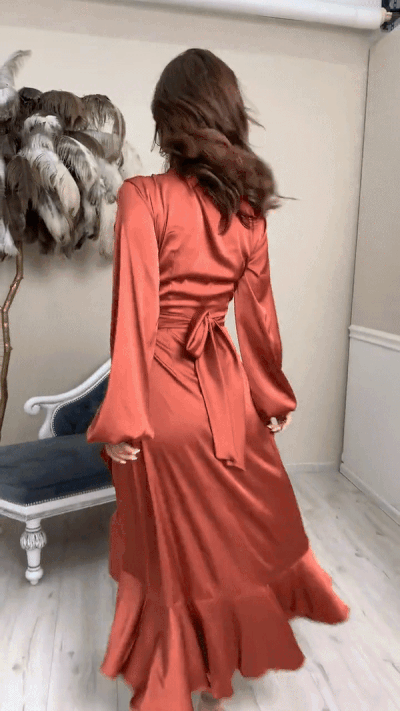Video of model wearing satin midi dress with bottom ruffle, balloon sleeves, and adjustable waist tie, walking in nude heels
