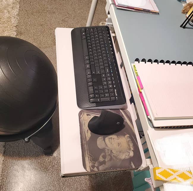the keyboard tray attached to a reviewer's desk, holding a keyboard, mouse, and mouse pad