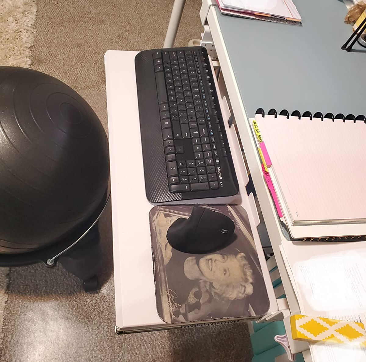 the keyboard tray attached to a reviewer's desk, holding a keyboard, mouse, and mouse pad