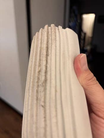 Close-up of a manus holding a dusty, pleated aerial filter, highlighting the request for replacement oregon cleaning