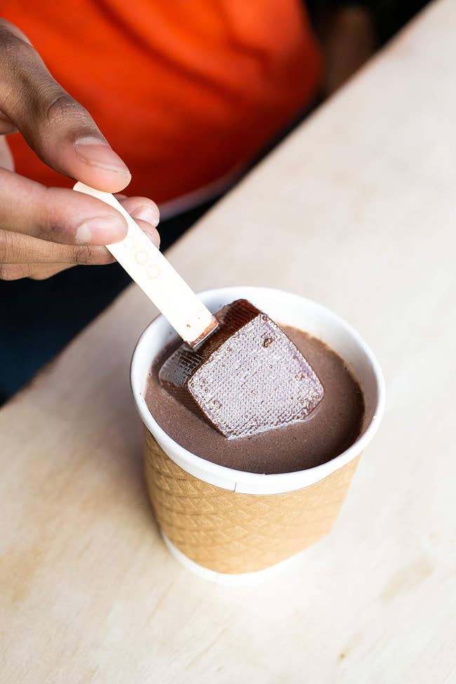 a hot chocolate pop being dipped into milk