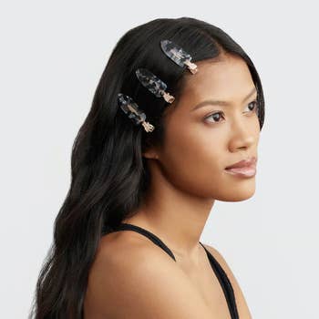 Model with three hair clips in her hair, looking to the side