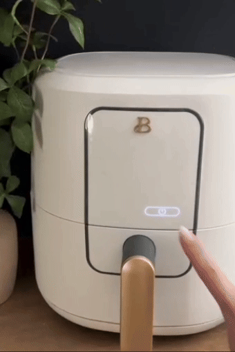 Person operates sleek, modern air fryer with a digital touchpad, ideal for trendy, efficient kitchen setups