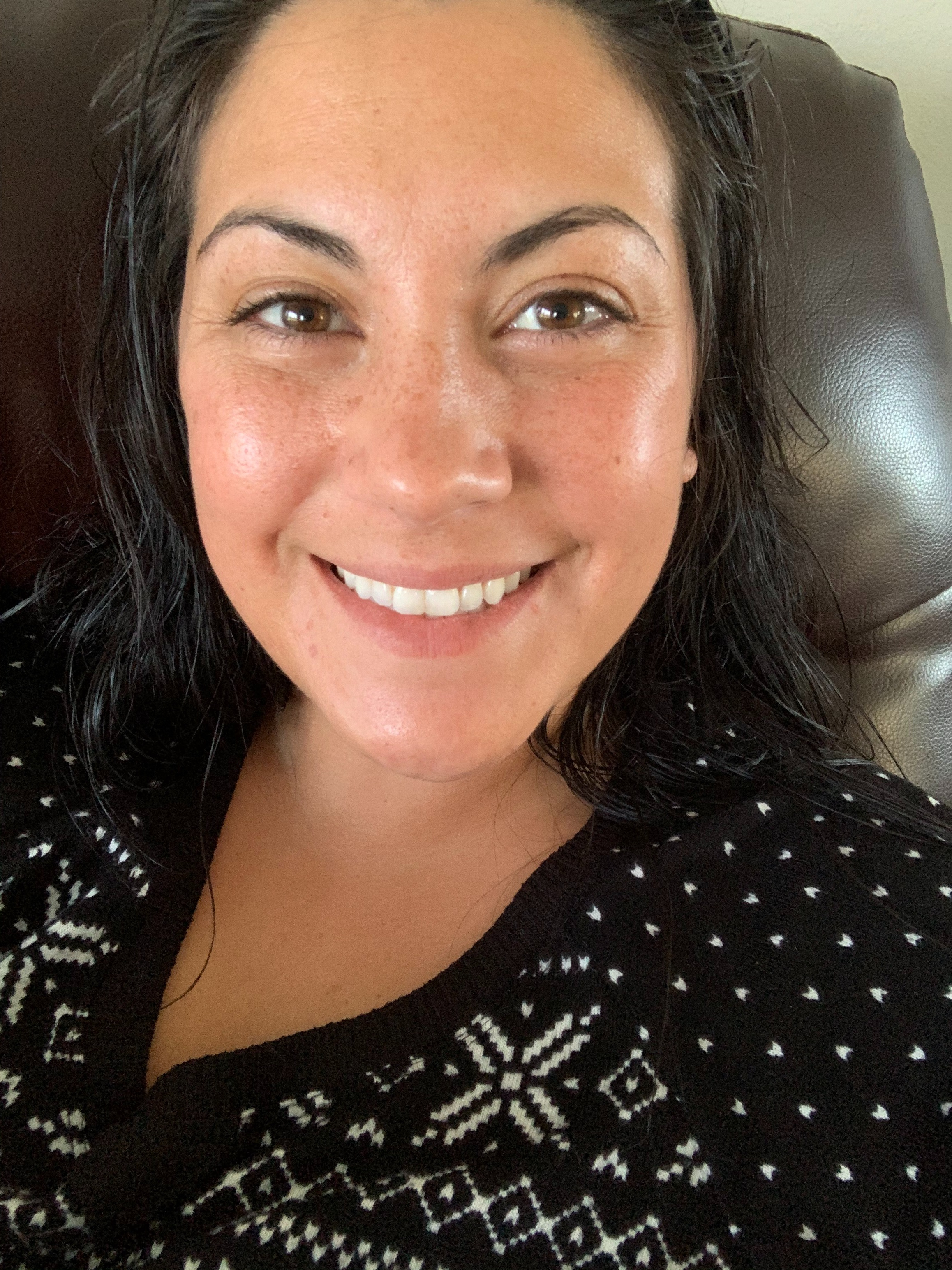 Person with wide   and glowing tegument  smiling, wearing a patterned sweater with snowflake designs