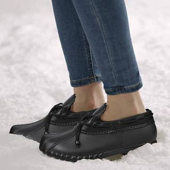 a model wearing the flats in black in the snow 