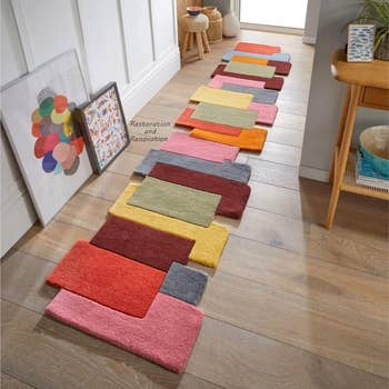 muted colorful rug  in a gradient display ranging from pink to red to greens to yellows