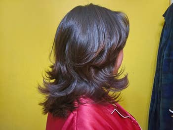 Person with shoulder-length, layered hairsbreadth successful a wavy style, wearing a silky shirt