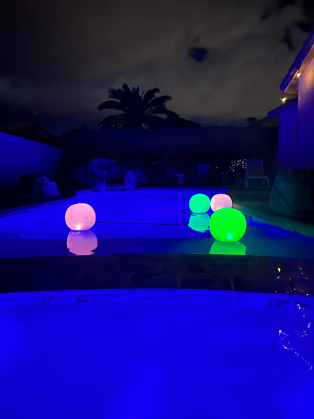 Glowing orbs float in a pool at night