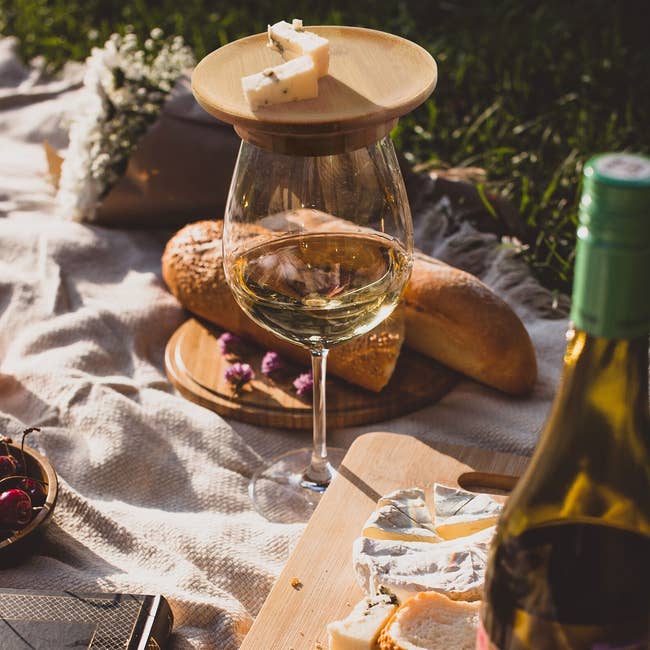 Picnic setting with a glass of wine, with a wooden cheese board on top