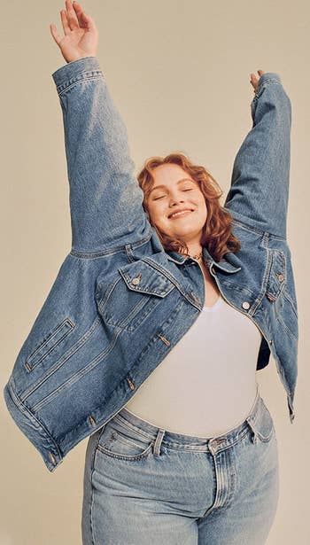 a model in the darker jean jacket with arms raised