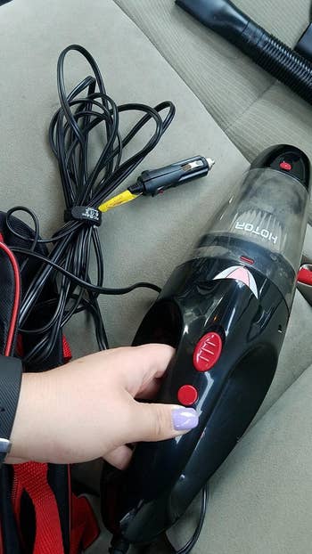 reviewer holding the vacuum with the car plug attached