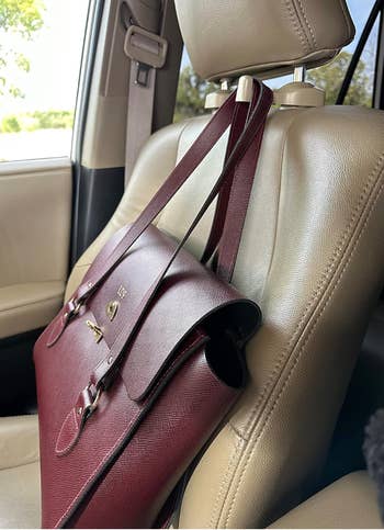 A leather handbag with metallic accents placed on a car seat