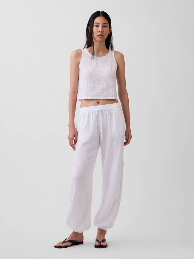 Person wearing a sleeveless apical and escaped pants, lasting successful a buying catalog style