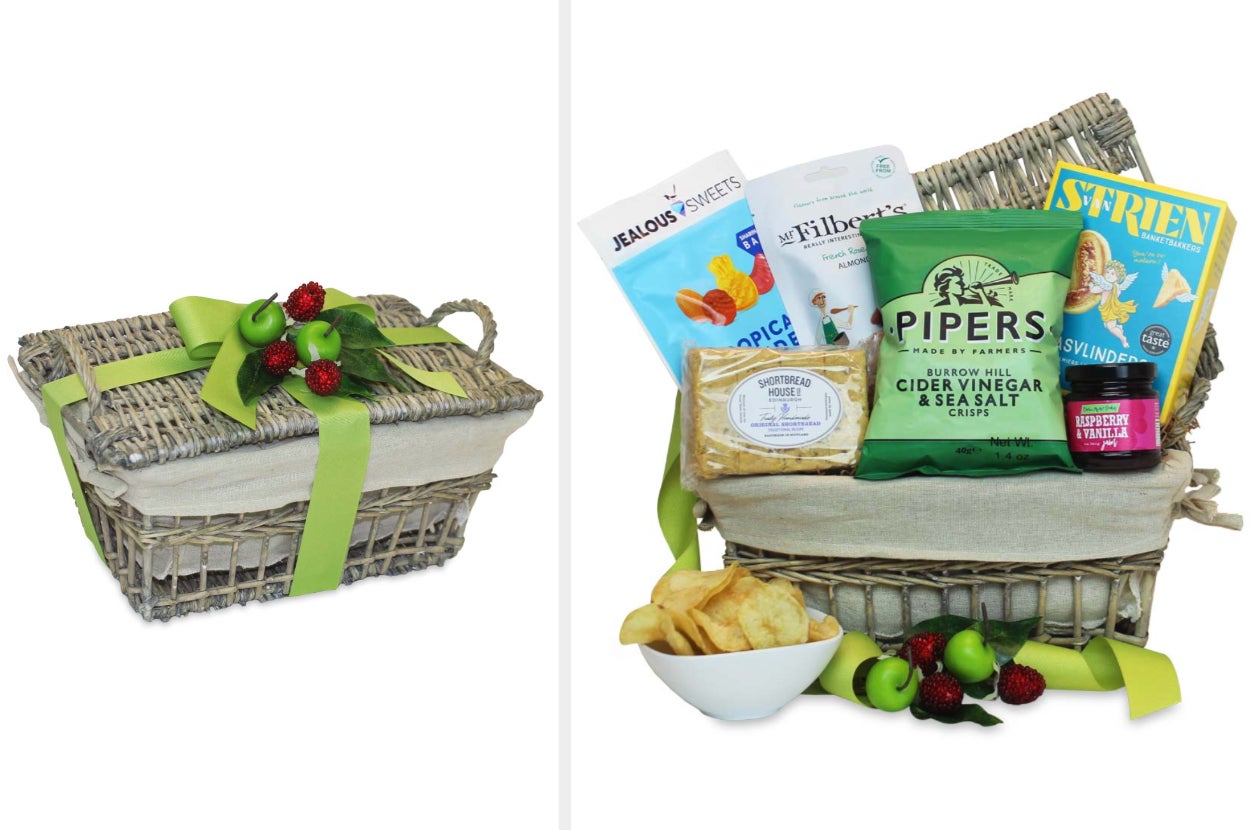 Beige wicker basket with green ribbon and fake fruit tied with a bow on top, product open with bags of chips, fruit snacks, crackers, shortbread, and jam