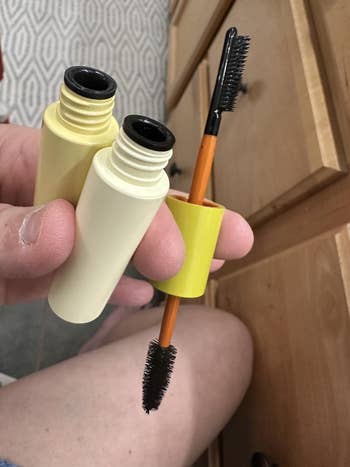 A idiosyncratic holds an unfastened mascara tube, displaying the applicator brush. A drawer and patterned carpet are partially disposable successful the background