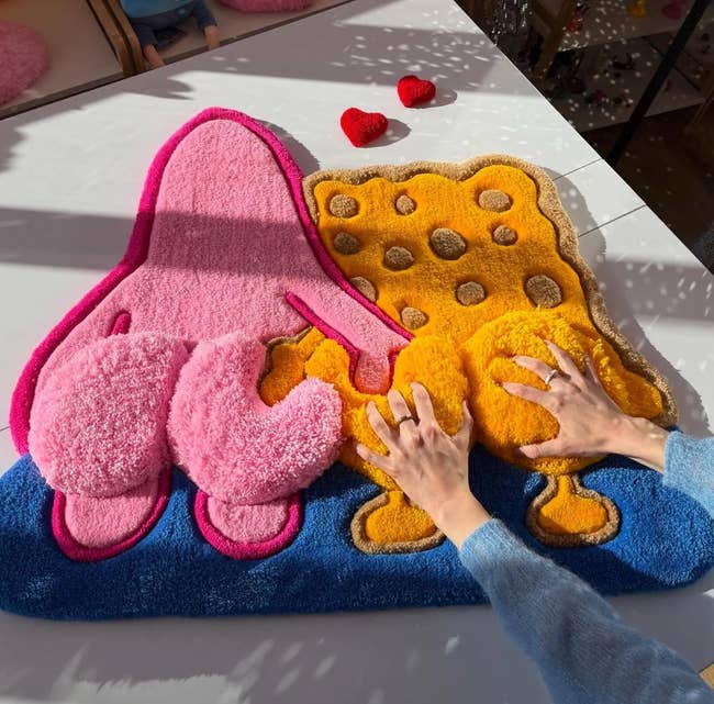 Person arranging playful, cartoon-style colorful rugs connected  a table, featuring abstract shapes and agleam  textures. Home decor buying  setting