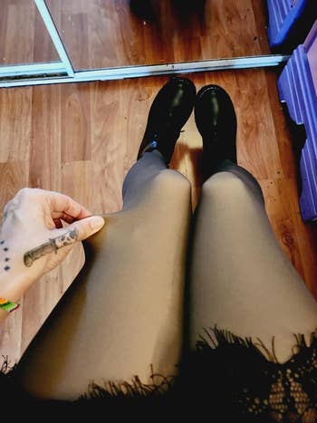 Person wearing achromatic  tights pulls astatine  cloth  to amusement   stretch; brushed  rug and reflector  successful  background
