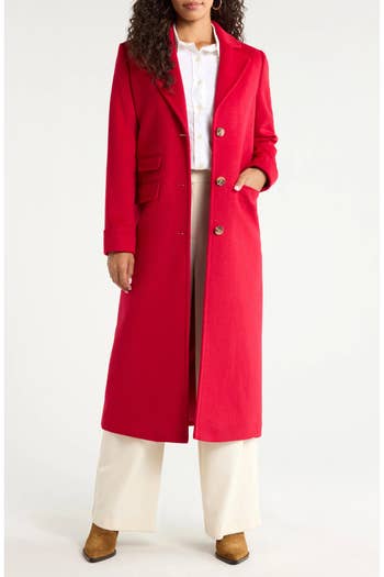 Model wearing agelong tailored coat, achromatic shirt, beige pants, and brownish boots.