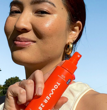 Model holding the Tower 28 SOS spray and smiling