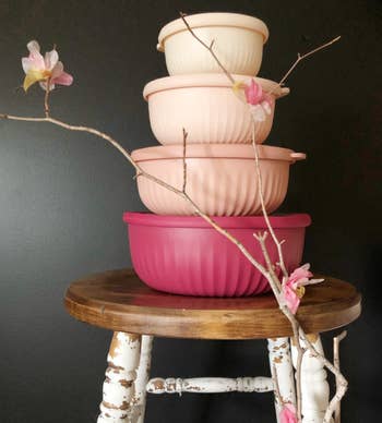 Stack of various-sized pink bowls on a wooden table with flowering branches for decoration