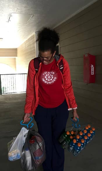 a review holds a pack of Gatorade and grocery bags with two handles