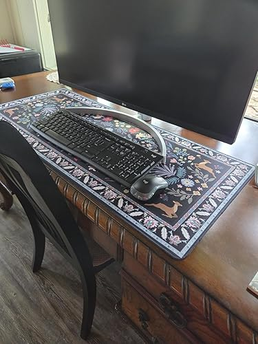 Desk setup with a large, decorative floral-patterned mouse pad, keyboard, and mouse in front of a monitor on a wooden table