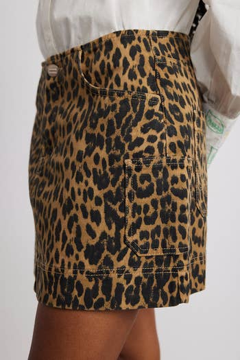A leopard print skirt with a button and pockets showcased for shopping
