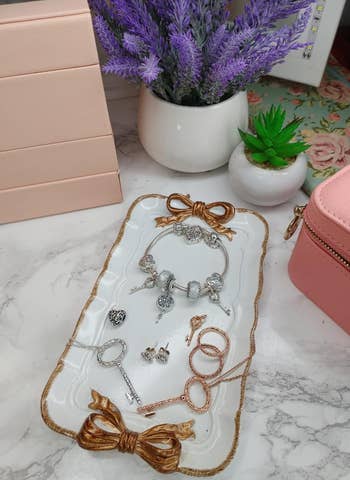 white rectangular vintage-style catch all with gold trim and gold bows on both ends 