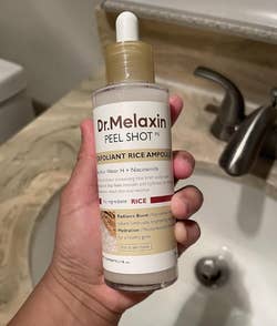 Person holding a bottle of Dr. Melaxin Peel Shot, an exfoliant with rice water and niacinamide, ideal for hydration and radiance enhancement
