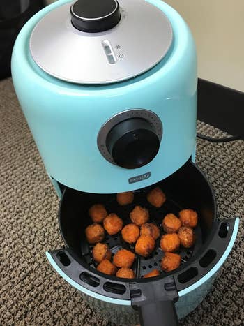 Compact air fryer with a basket of food, showcasing a kitchen appliance for healthy cooking options