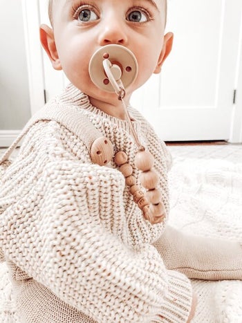 a child with a pacifier in his mouth attached to the pacifier clip