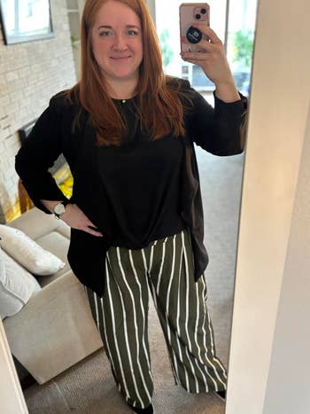 Woman successful a achromatic apical and striped wide-leg pants takes a reflector selfie, showcasing a casual yet stylish outfit