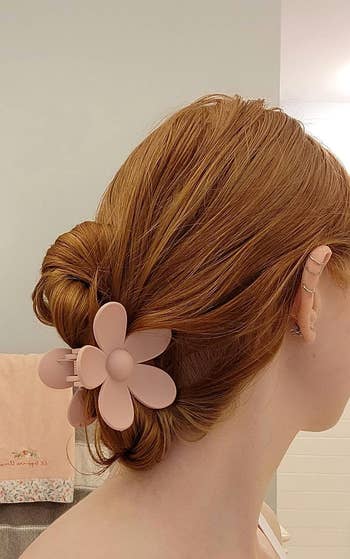 a reviewer with a pale pink flower-shaped clip holding a bun in their hair