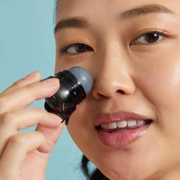Woman applying skincare roller to face, highlighting a self-care routine