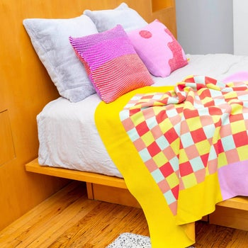 a multicolored checkered throw blanket draped over a bed