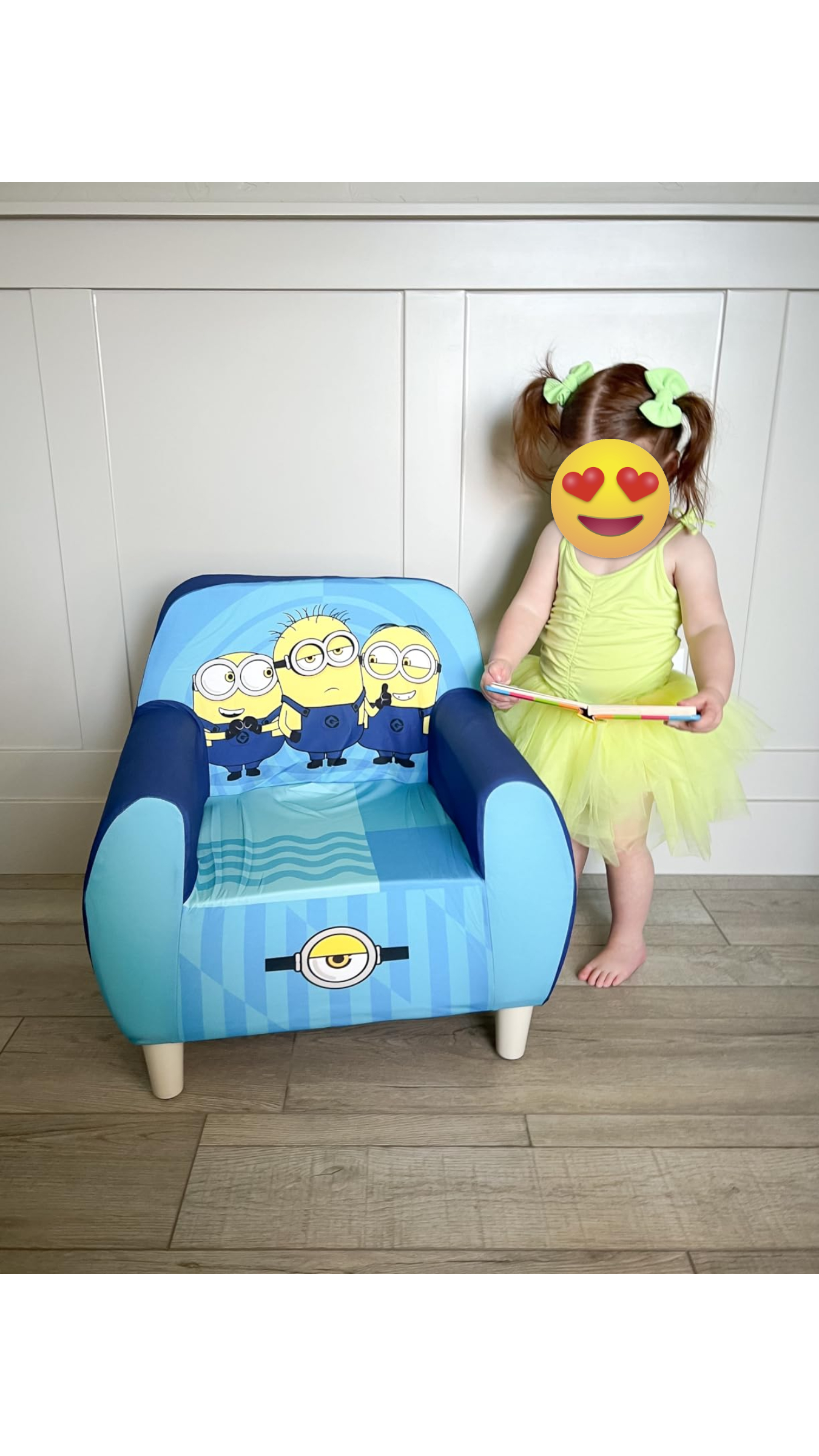 Child with a blurred look   successful  a greenish  formal  stands beside a tiny  seat  featuring Minions graphics