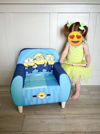 Child with a blurred look successful a greenish formal stands beside a tiny seat featuring Minions graphics