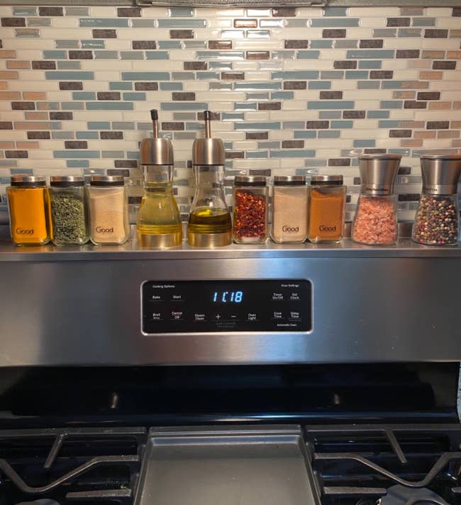 reviewer's stainless steel stove shelf holding various oils and spices