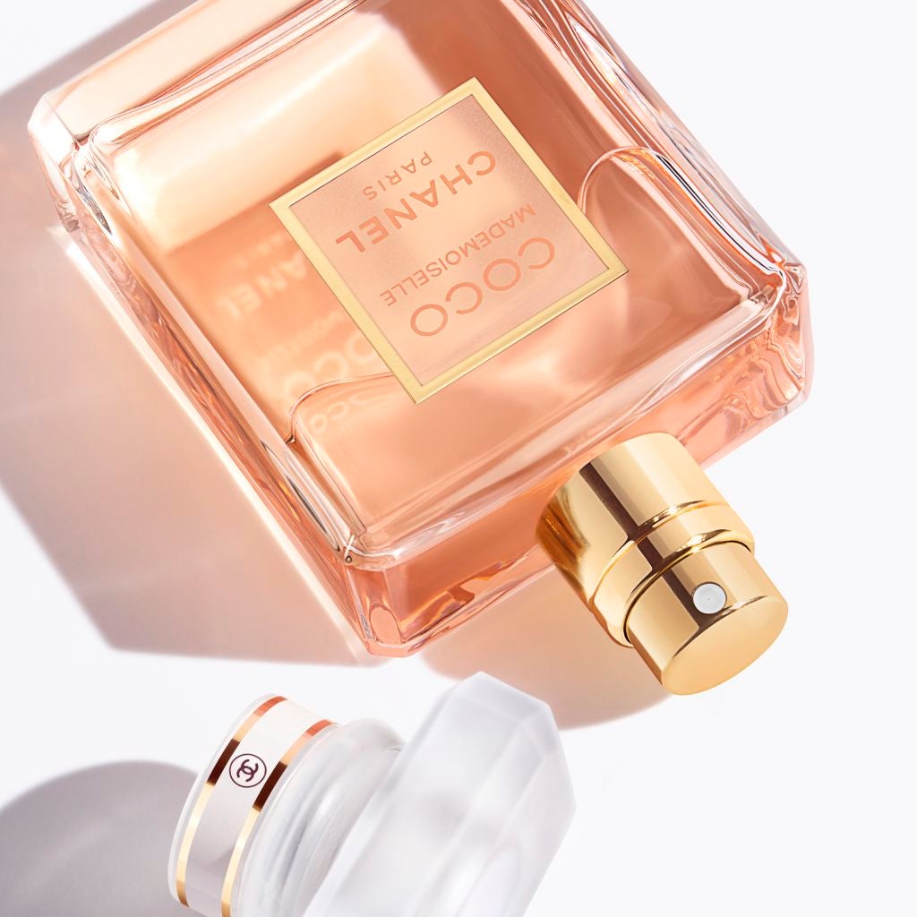 the bottle of perfume laying on its side next to its cap