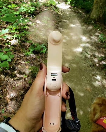 reviewer using the pink fan while walking in the woods