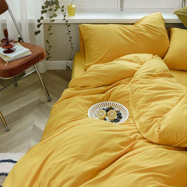 plush yellow duvet on flatform bed with fruit on a plate on top