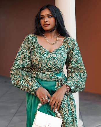 model wearing green long-sleeve surplice top with paisley design
