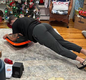Person exercising on an orange core trainer in a room with a Christmas tree and festive decorations
